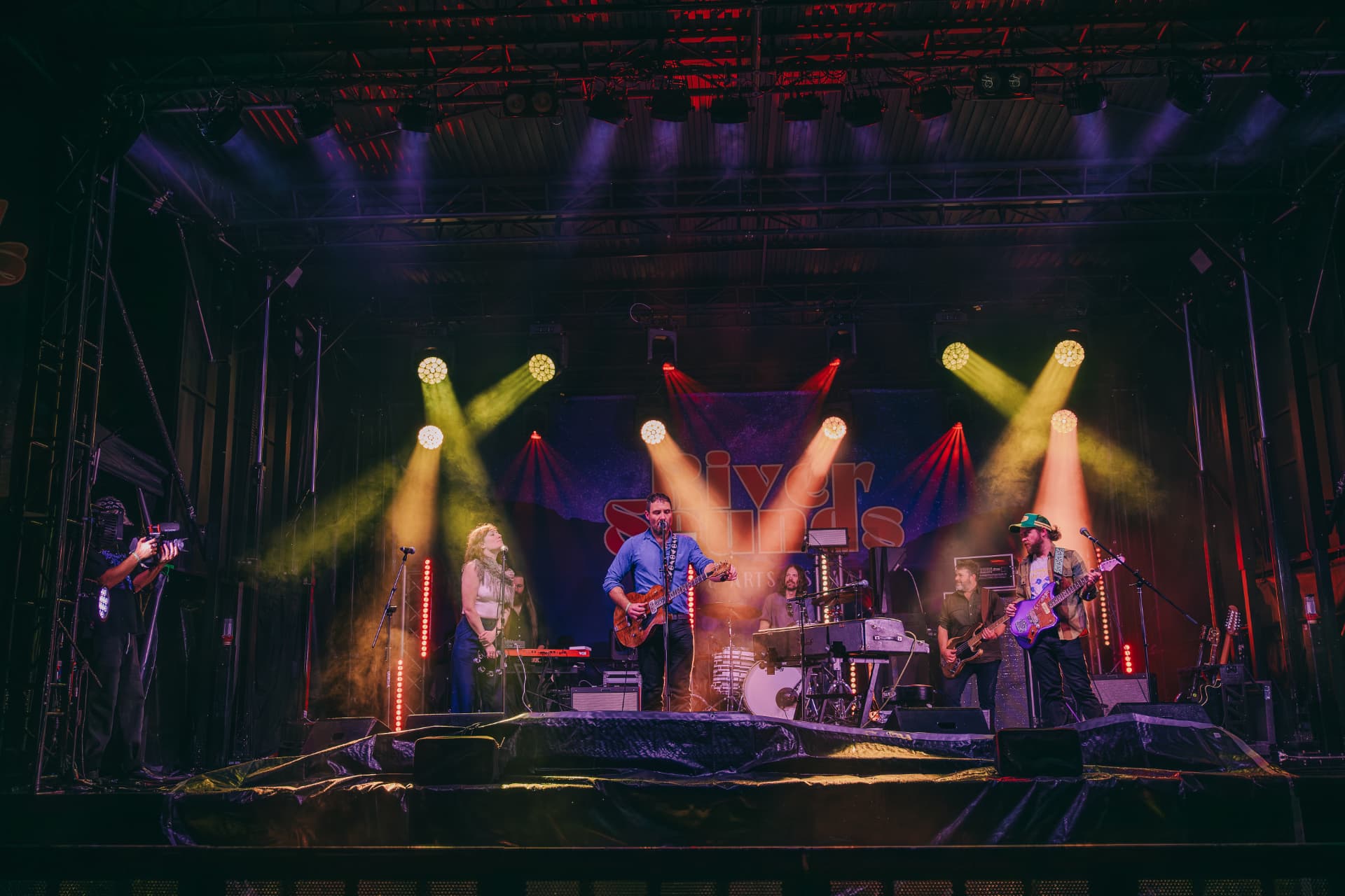 Full band on stage under yellow lights