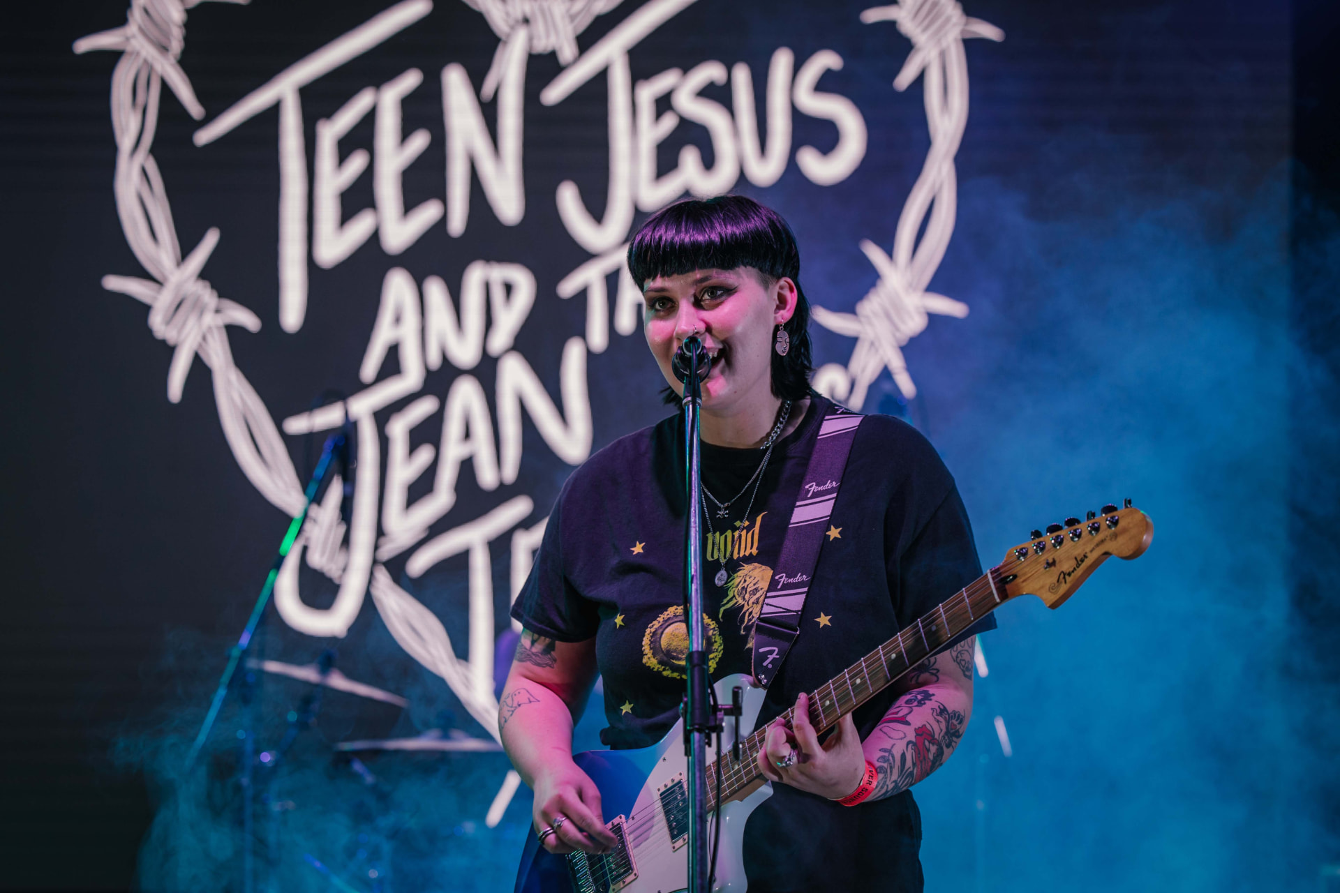 Musician playing a white electric guitar on a smoke-filled stage