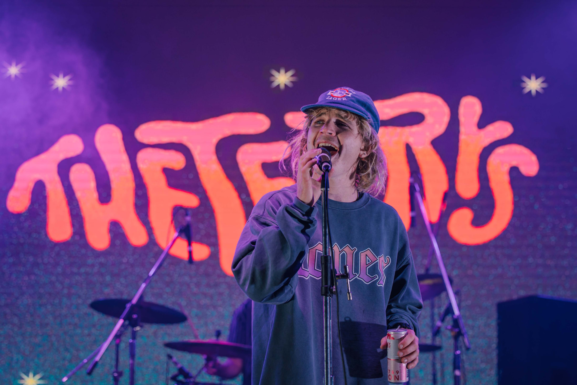 Singer gripping a microphone under purple stage lights