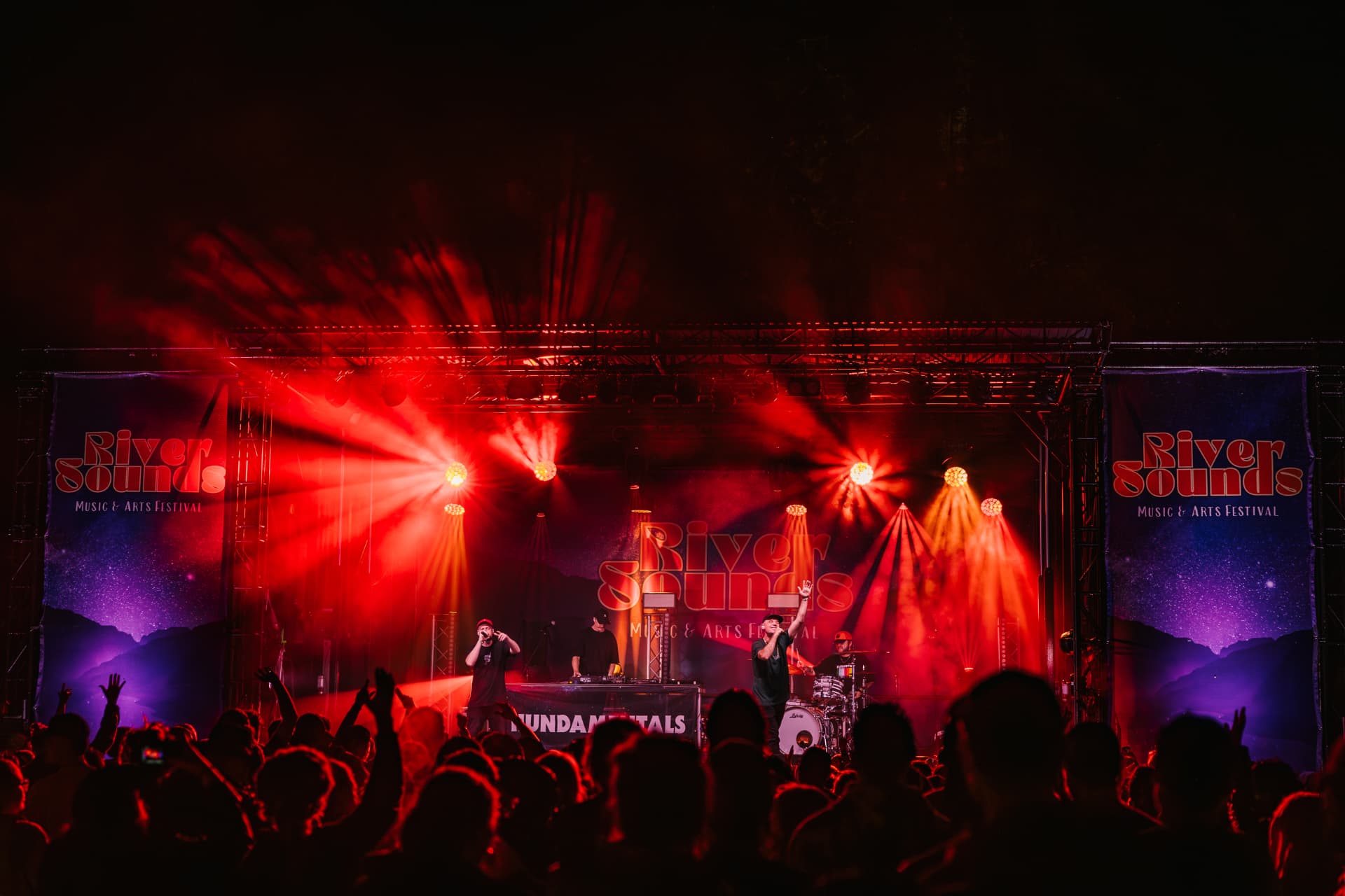 Packed crowd facing a red-lit stage
