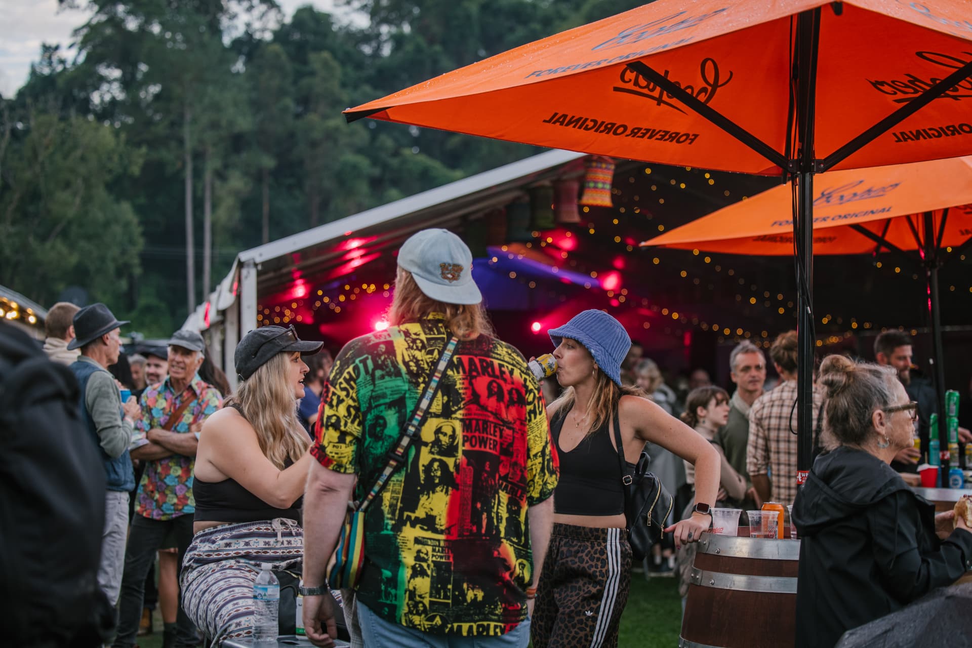 Festival-goers relaxing under orange umbrellas