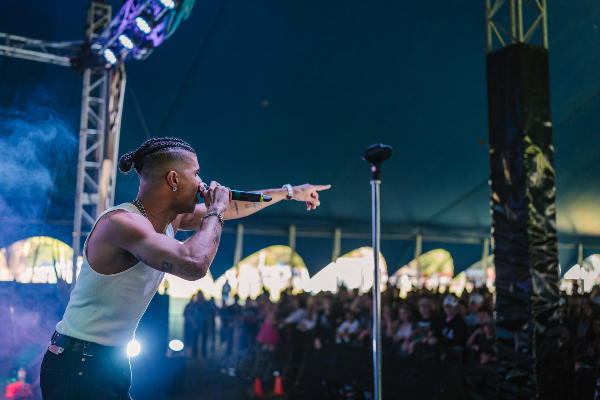 Performer singing to a tented crowd under violet lights
